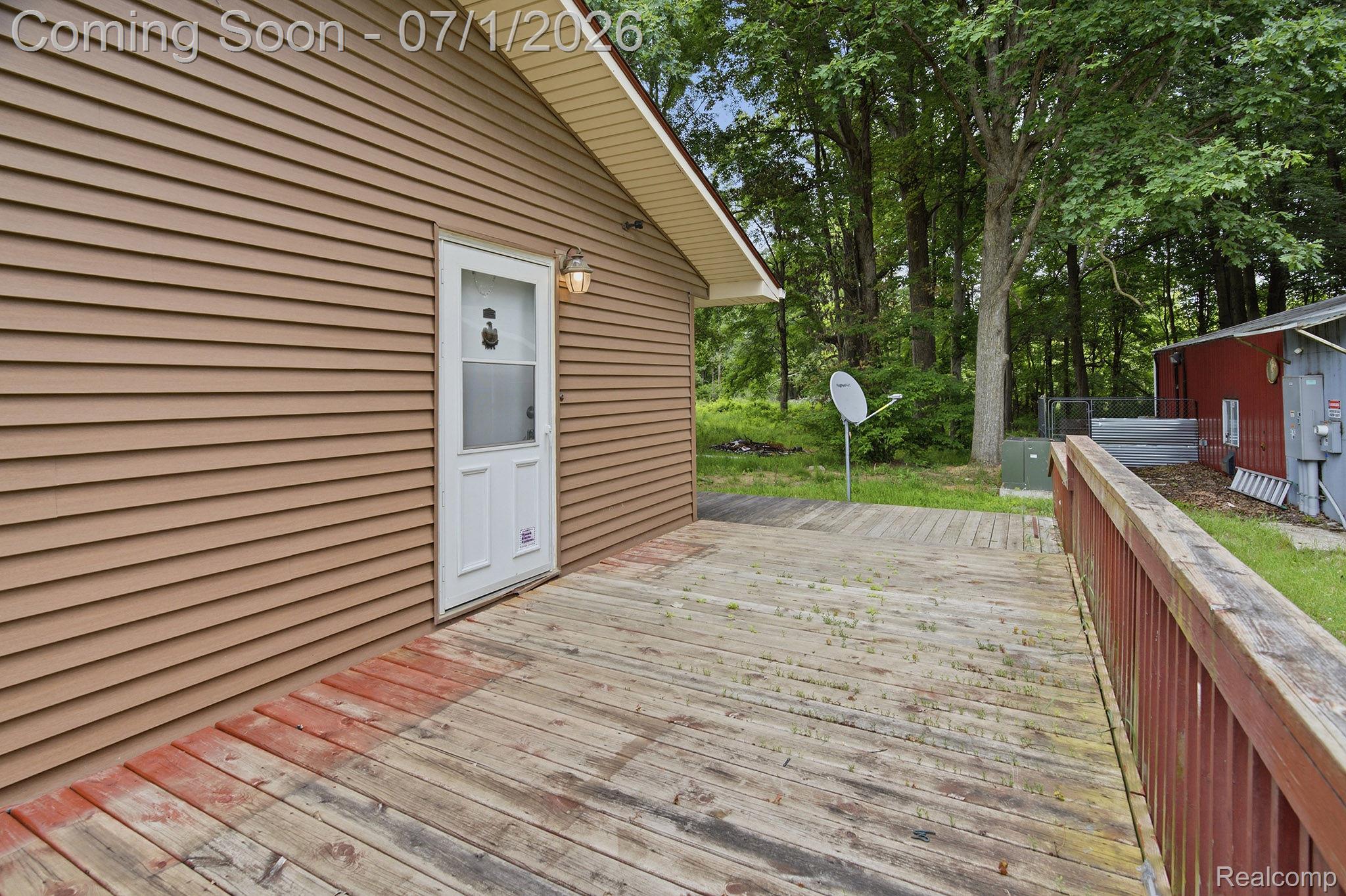 Wood-finish decking with a red-toned railing and a white entry door