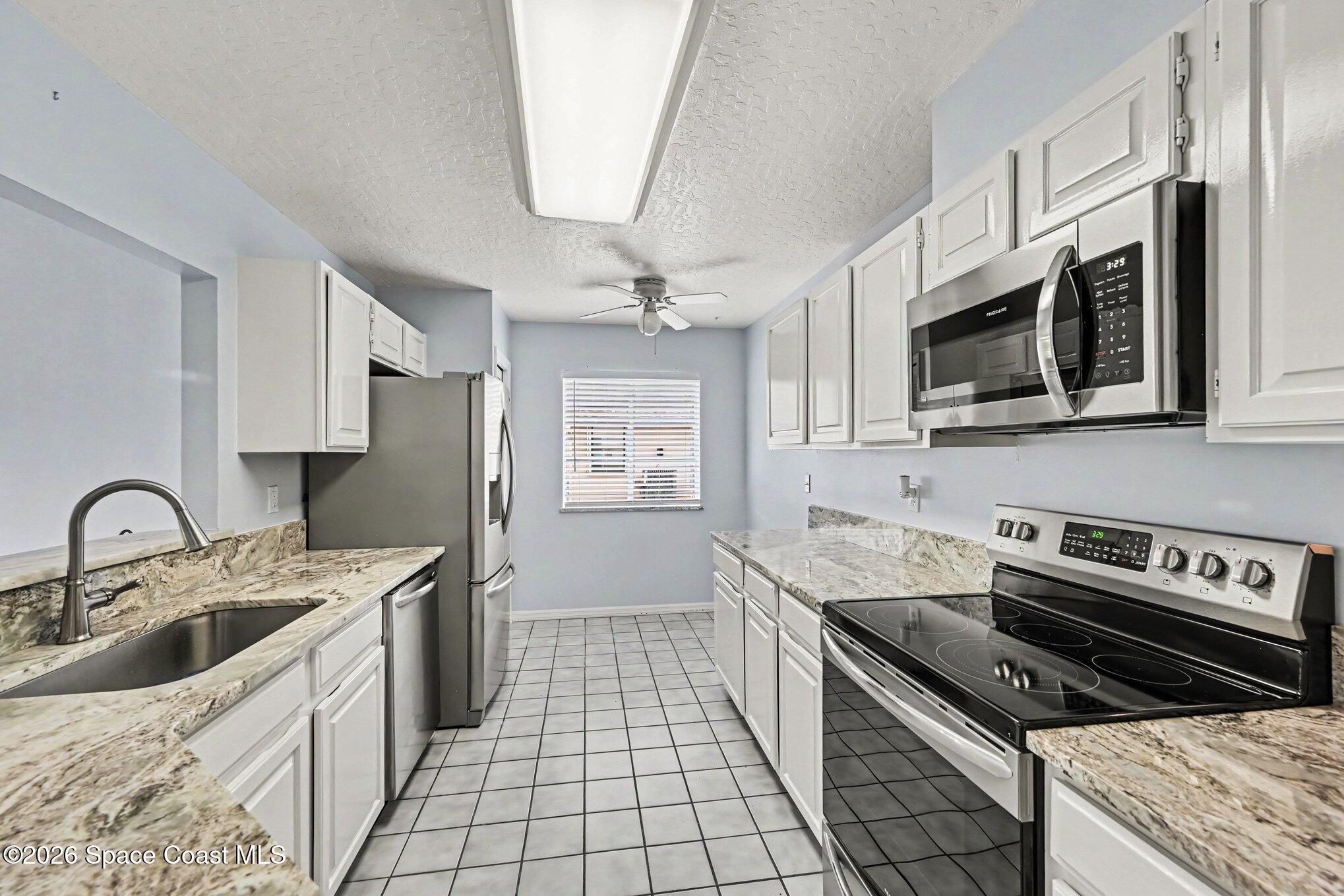 899 Ridge Lake Drive Melbourne, FL 32940 - Photo 9 of 34 a kitchen with stainless steel appliances a sink a stove a microwave a sink a refrigerator and cabinets