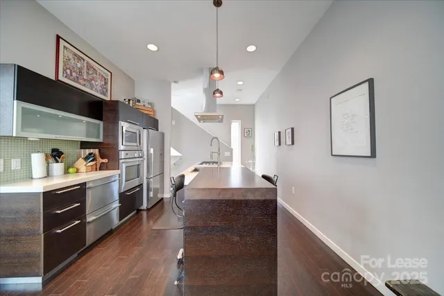 a large kitchen with stainless steel appliances granite countertop a lot of counter space and wooden floor