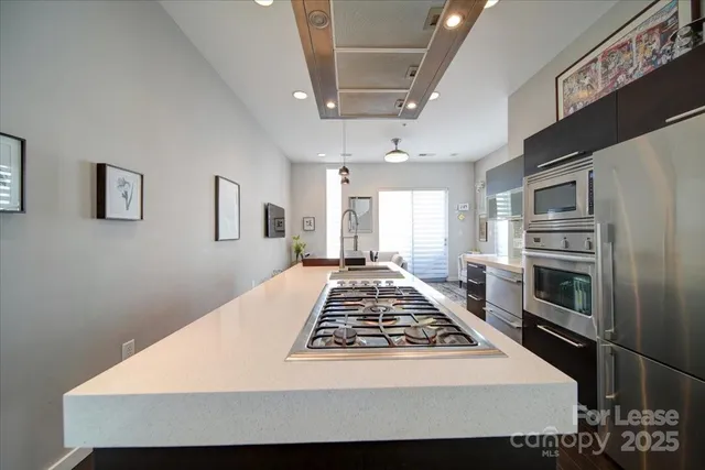 a large white kitchen with a stove a refrigerator a sink dishwasher and cabinets