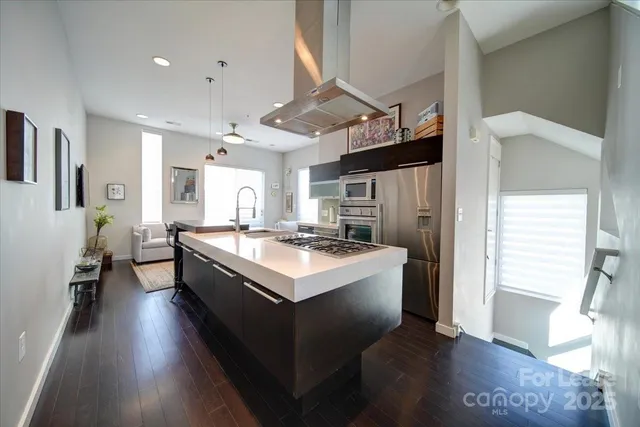 a large white kitchen with kitchen island a stove a refrigerator a sink dishwasher and a fireplace with wooden floor