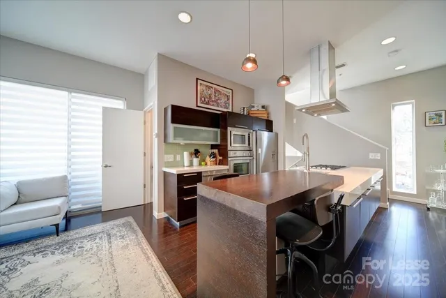 a kitchen with stainless steel appliances kitchen island granite countertop a table chairs and a refrigerator