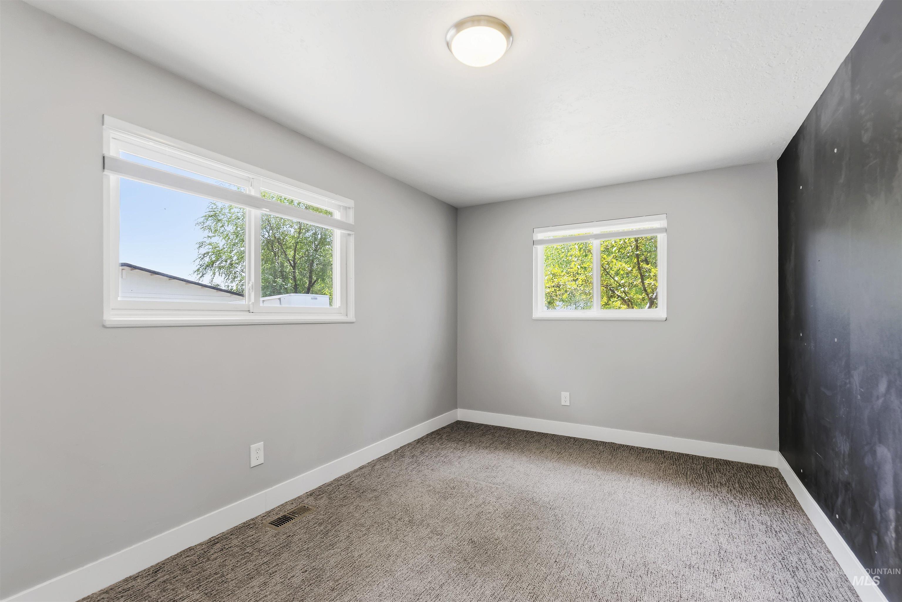 355 East Beacon Light Road Eagle, ID 83616 - Photo 23 of 47 Room featuring two windows with white blinds, grey wall paint, and a dark accent wall