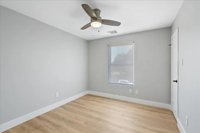an empty room with a window and ceiling fan