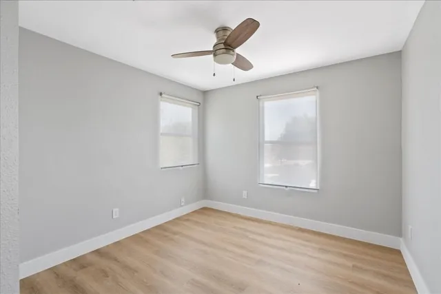an empty room with a window and ceiling fan