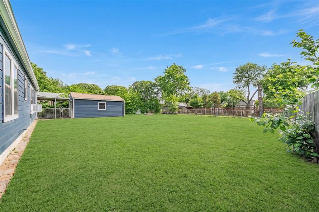 1802 Keneipp Road Carrollton, TX 75006 - Photo 20 of 22 The property features an extensive lawn with a wooden fence and mature trees
