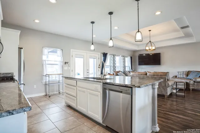 a kitchen with kitchen island granite countertop a sink a counter space appliances and cabinets
