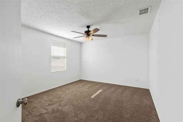 an empty room with a window and a ceiling fan