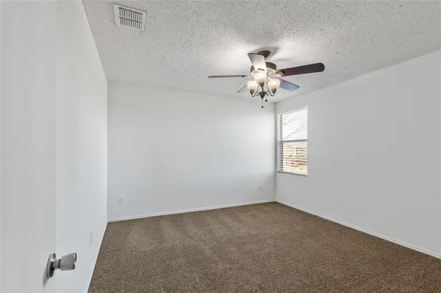 an empty room with a window and a fan
