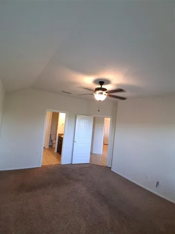 an empty room with chandelier fan and windows