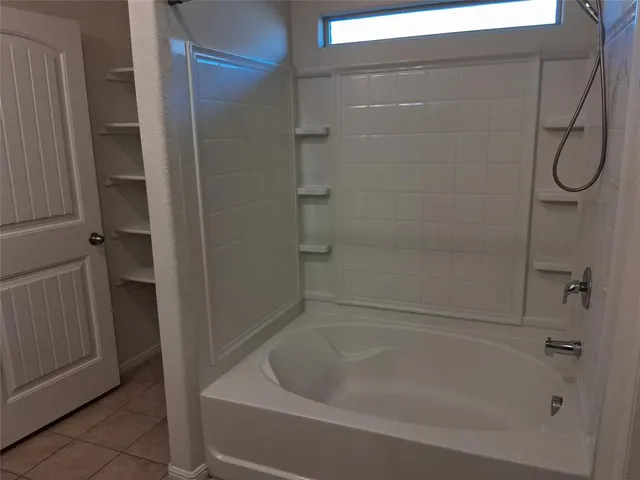 a bathroom with a bath tub with a glass door shower
