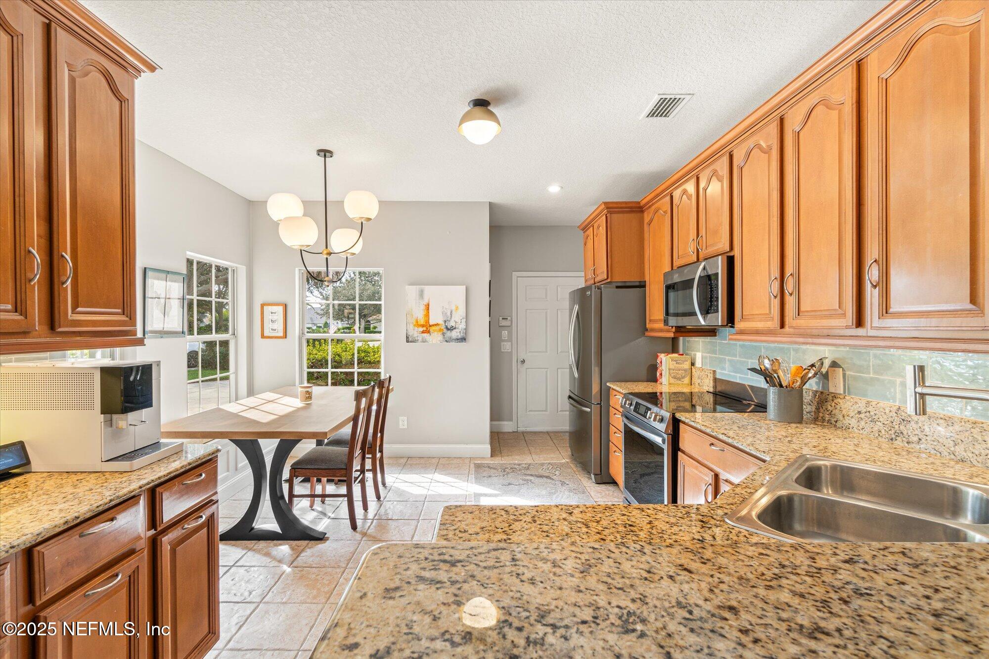 606 Teeside Court St. Augustine, FL 32080 - Photo 12 of 47 a kitchen with stainless steel appliances granite countertop sink microwave and wooden cabinets