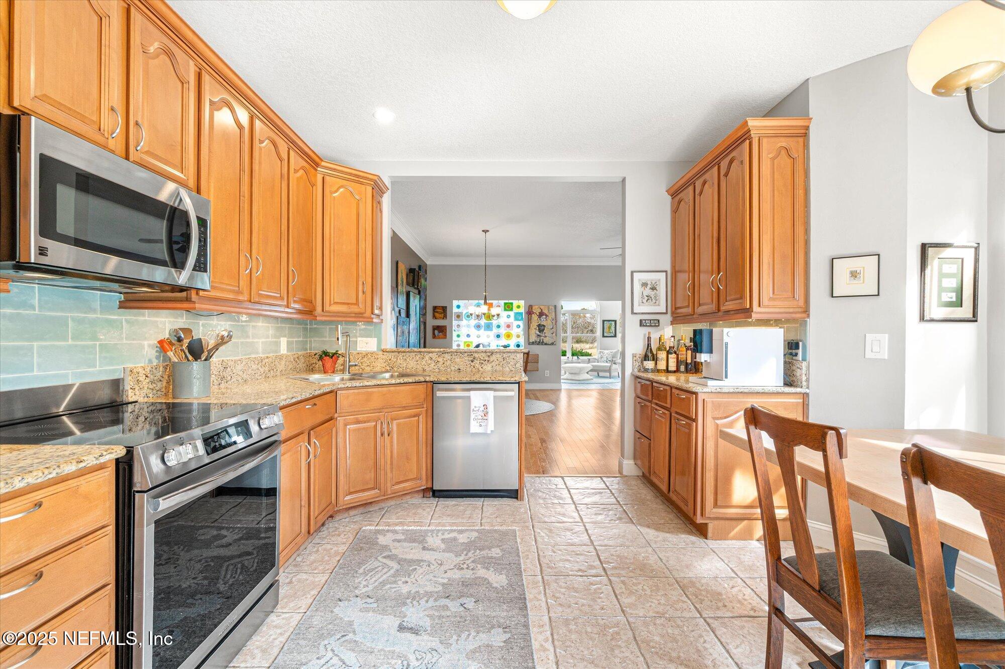 606 Teeside Court St. Augustine, FL 32080 - Photo 13 of 47 a kitchen with stainless steel appliances granite countertop a stove a sink dishwasher and a microwave oven with white cabinets