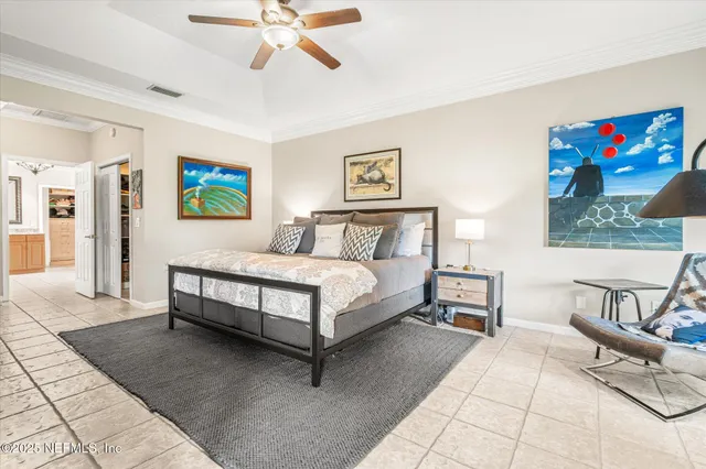 a spacious bedroom with a bed a painting on the wall and a potted plant