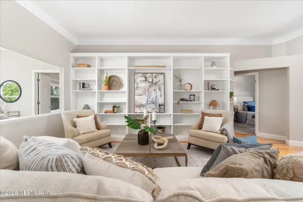 a living room with furniture and a large mirror next to a window