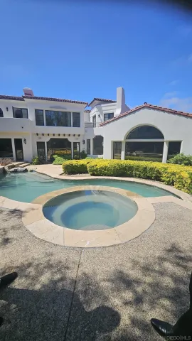 a view of a large pool with lawn chairs under an umbrella