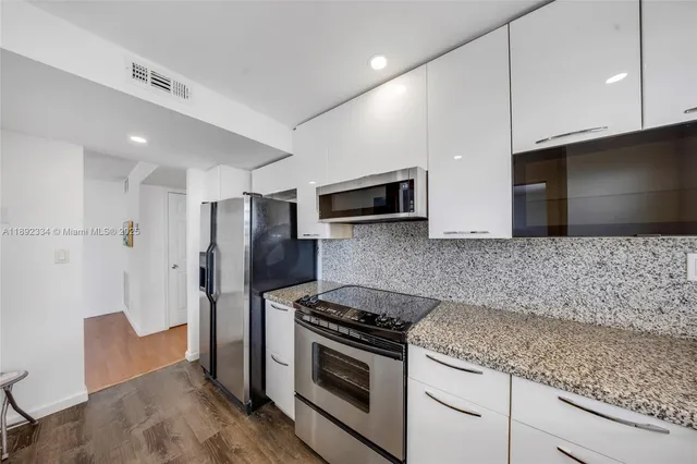 a kitchen with stainless steel appliances granite countertop a stove a microwave and a refrigerator