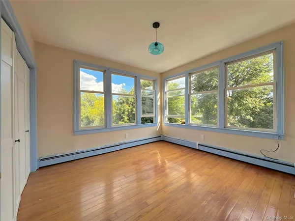 a view of an empty room with a window and wooden floor