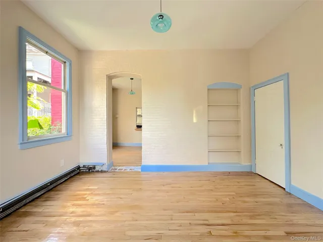 a view of an empty room with window and wooden floor