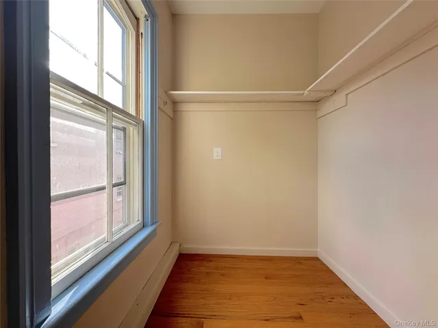 a view of an empty room with a window and wooden floor