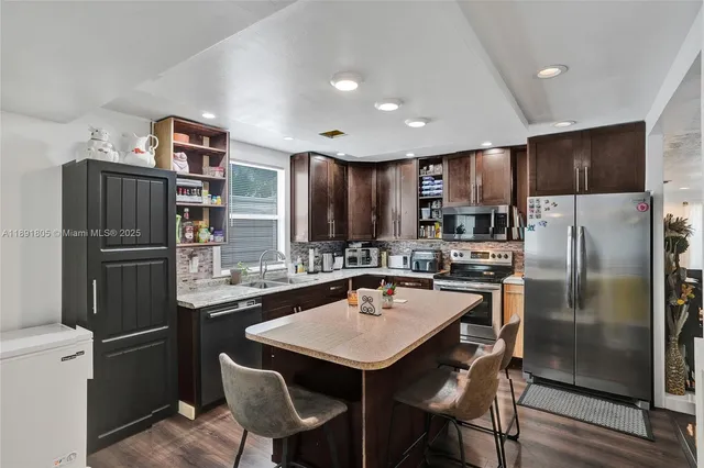 a kitchen with stainless steel appliances a refrigerator a stove a sink a dining table and chairs