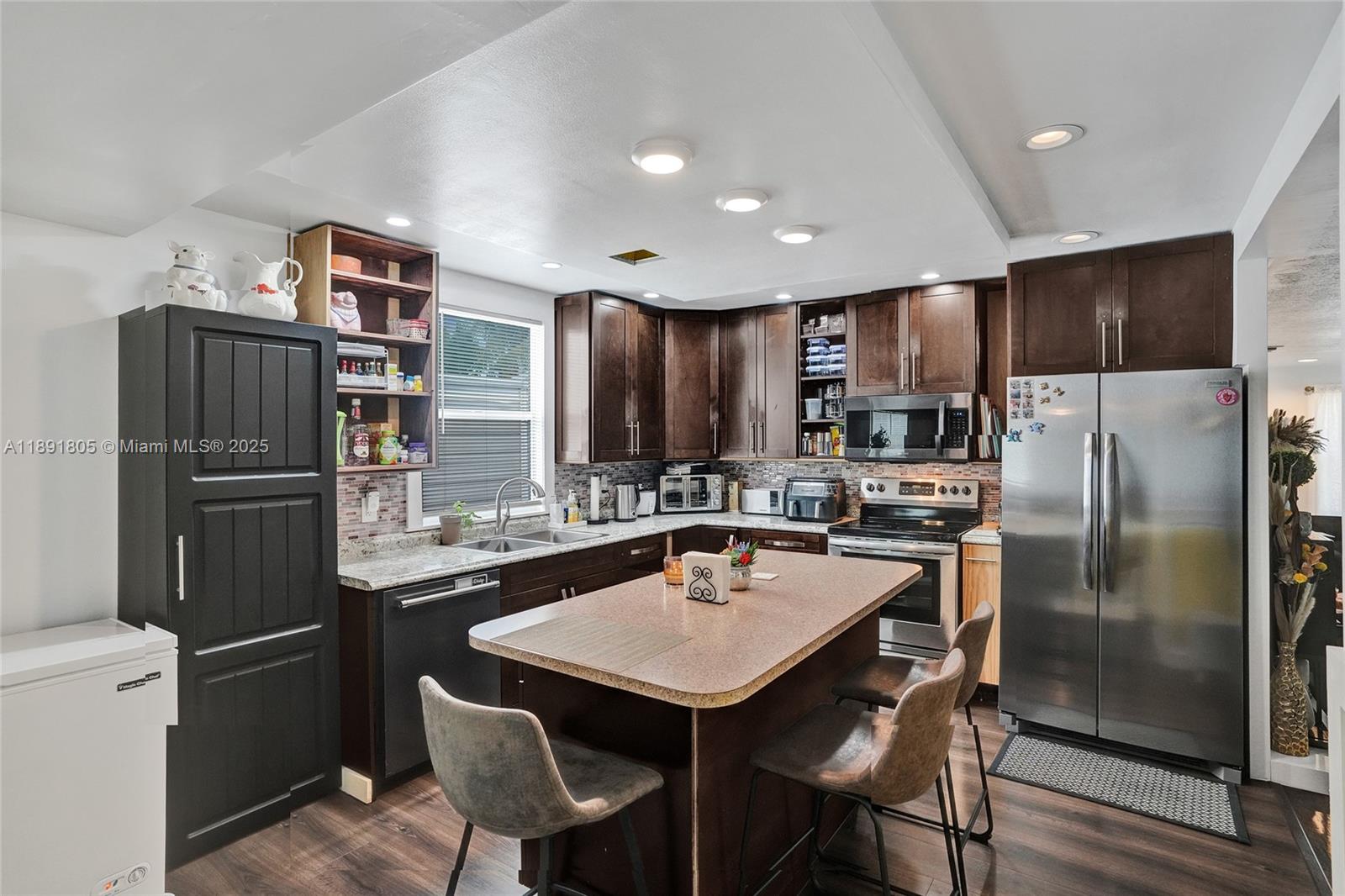 11201 Southwest 55th Street Miramar, FL 33025 - Photo 17 of 38 a kitchen with stainless steel appliances a refrigerator a stove a sink a dining table and chairs
