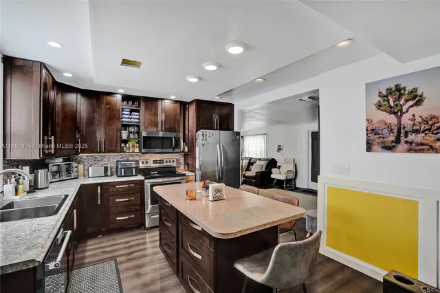 a kitchen with kitchen island granite countertop a sink appliances and cabinets