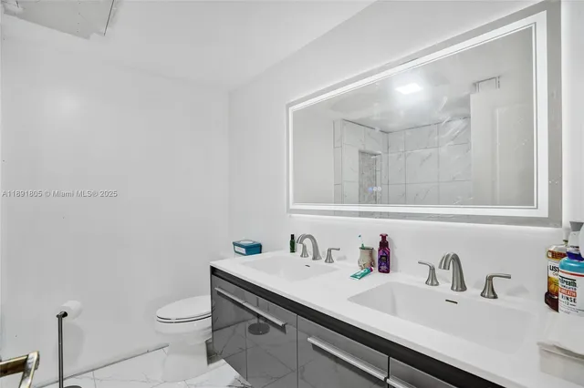 a bathroom with a sink vanity mirror and toilet