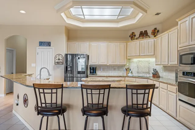 a kitchen with stainless steel appliances granite countertop a kitchen island a stove a table and chairs
