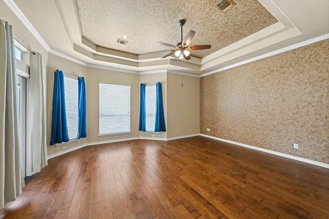 a view of an empty room with a window and wooden floor