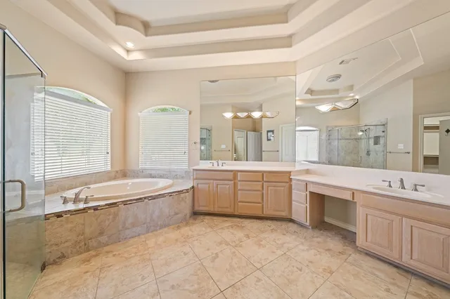 a large bathroom with a large tub sink vanity granite and a large mirror