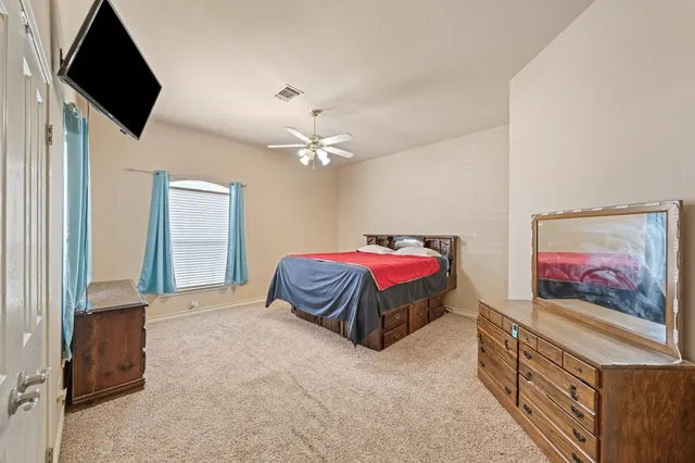 a spacious bedroom with a bed and a flat screen tv