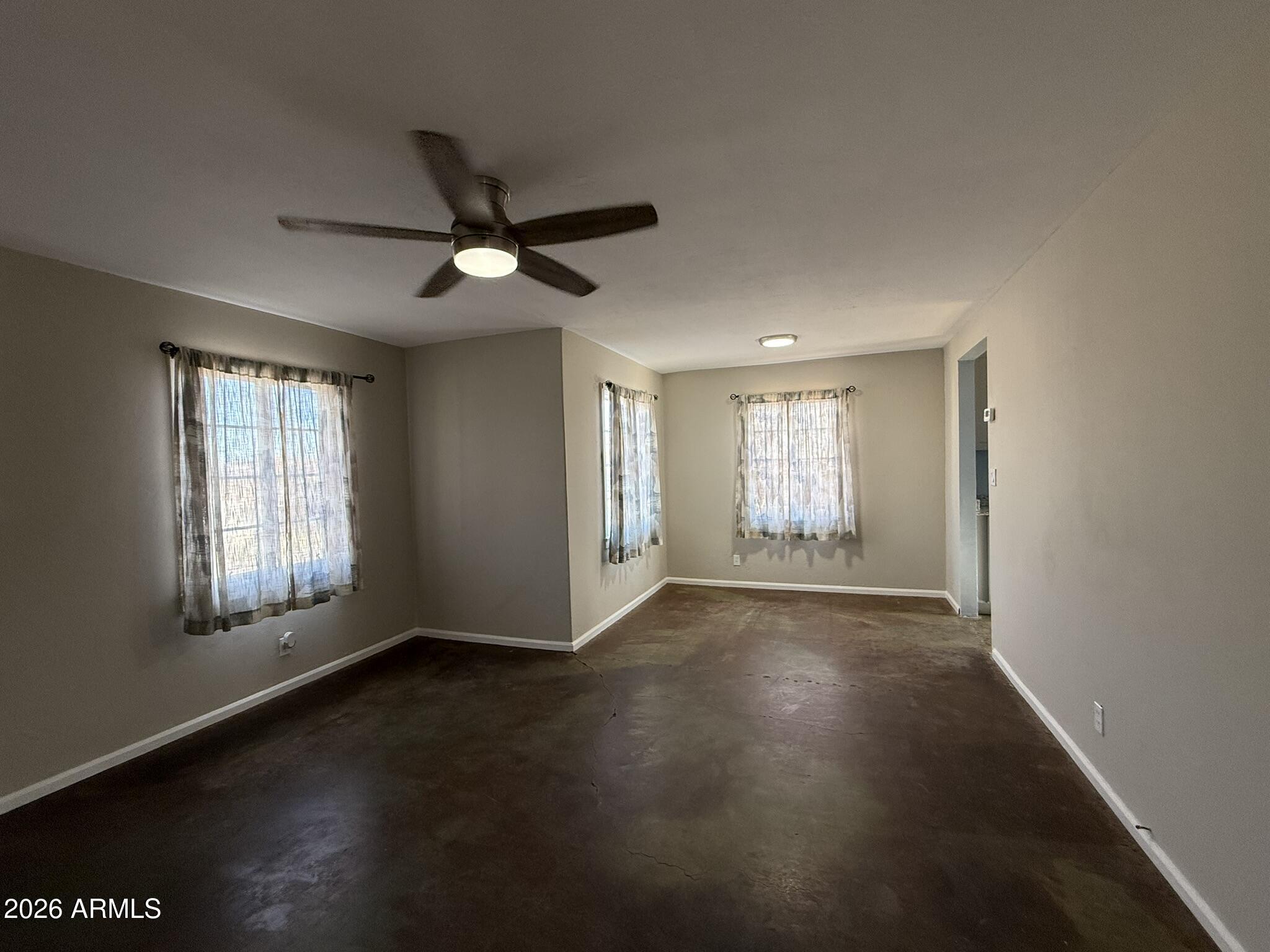 91 Neptune Avenue Bisbee, AZ 85603 - Photo 2 of 12 a view of an empty room with a window and wooden floor