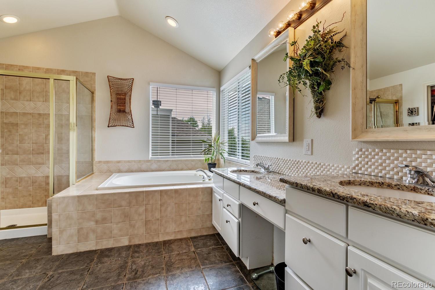 6966 South Riviera Street Aurora, CO 80016 - Photo 17 of 30 a spacious bathroom with a granite countertop tub sink and mirror