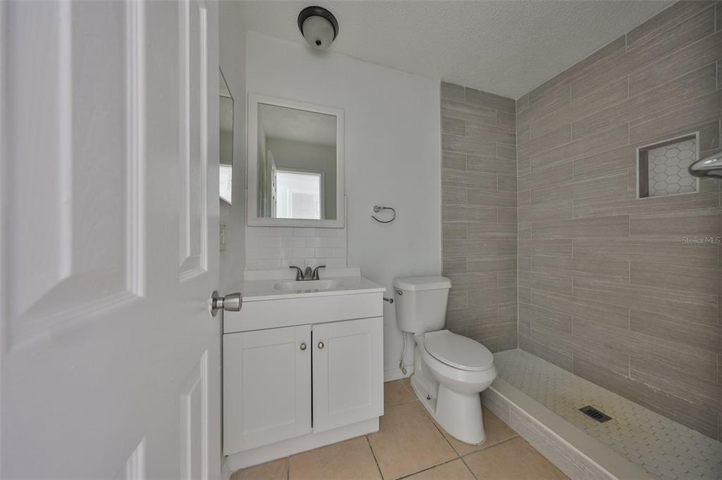 11708 Balm Riverview Road Riverview, FL 33569 - Photo 31 of 37 a bathroom with a granite countertop toilet a sink a mirror and a shower