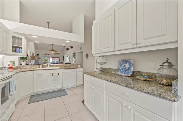 a kitchen with granite countertop white cabinets and white appliances