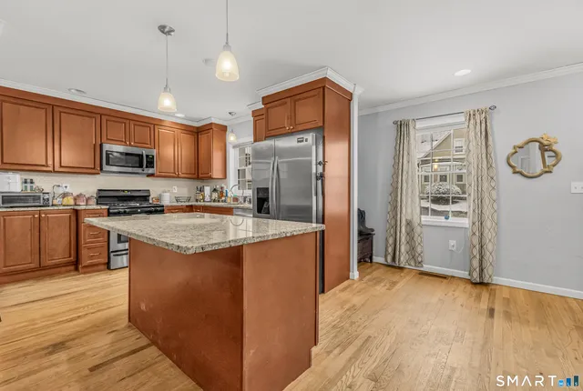 a kitchen with stainless steel appliances granite countertop a refrigerator a stove top oven a sink and dishwasher with wooden floor