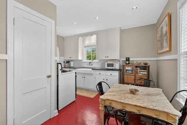 a kitchen with kitchen island a stove a sink a refrigerator dining table and chairs