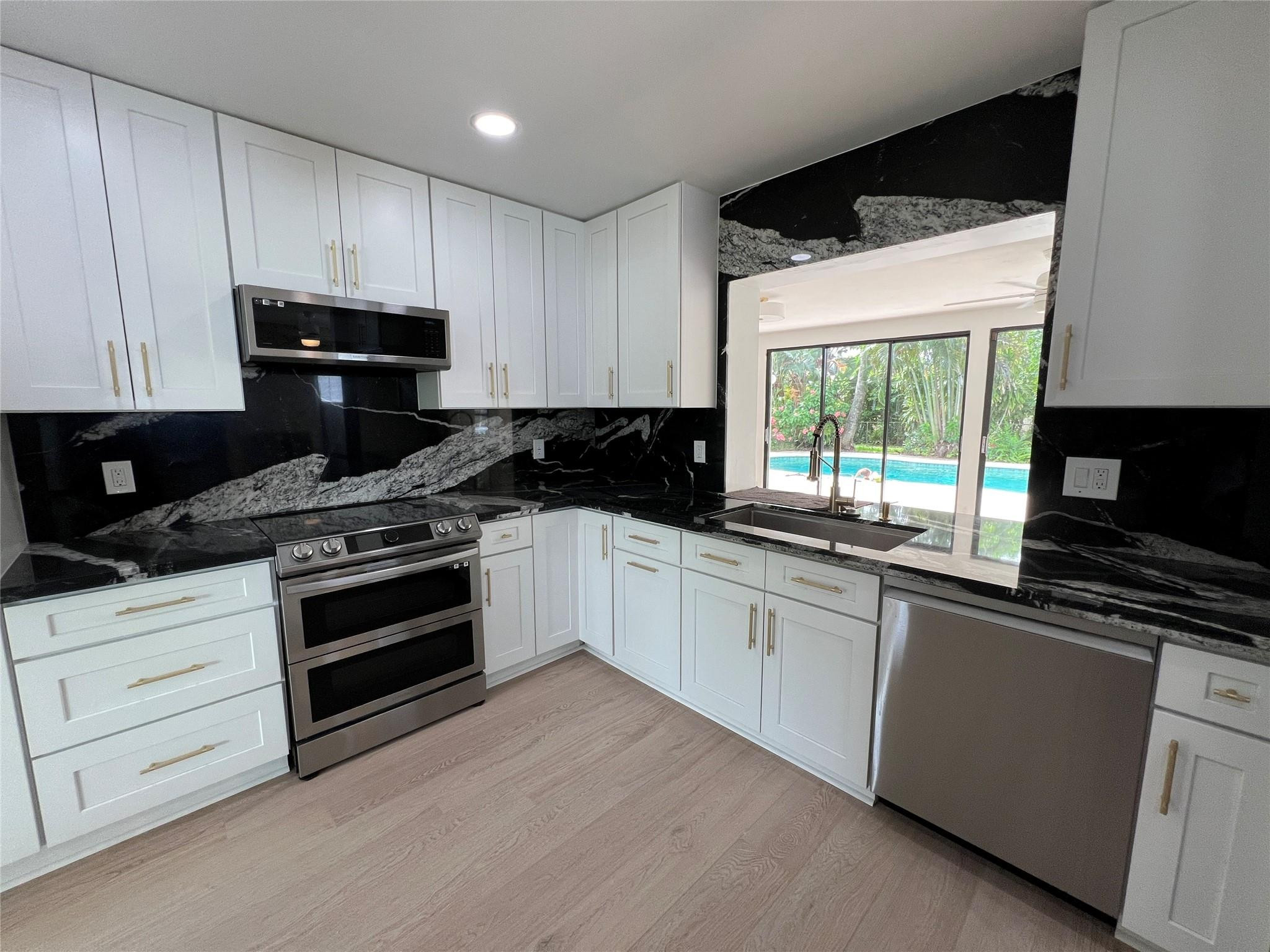 4408 Monroe Street Hollywood, FL 33021 - Photo 8 of 26 a kitchen with granite countertop a stove a sink and a microwave