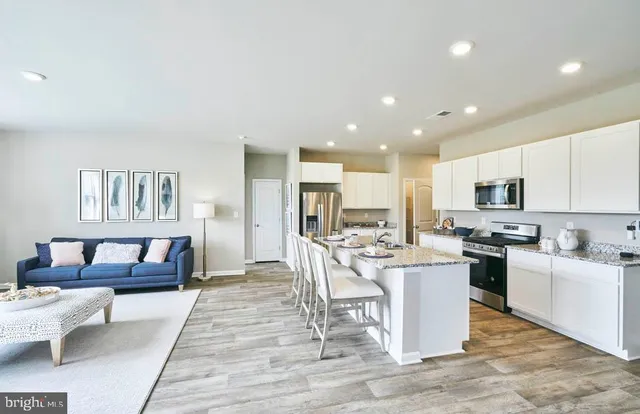 a living room with stainless steel appliances furniture and a kitchen view
