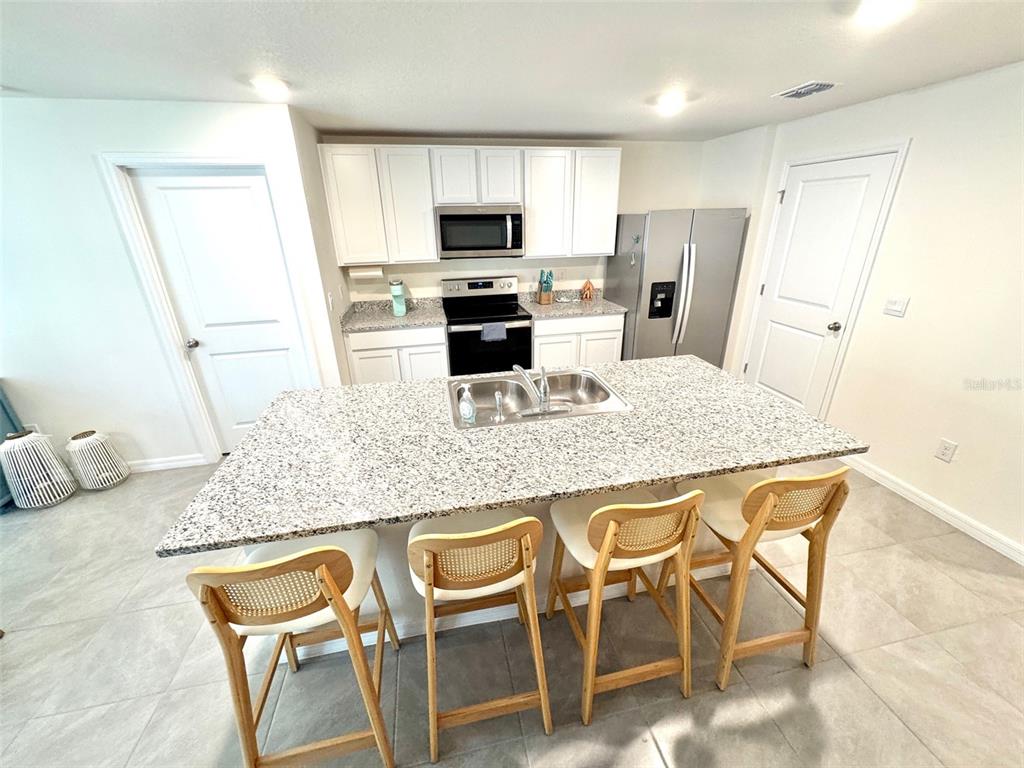 13374 Mylion Way Spring Hill, FL 34610 - Photo 5 of 39 a kitchen with granite countertop kitchen island cabinets and refrigerator