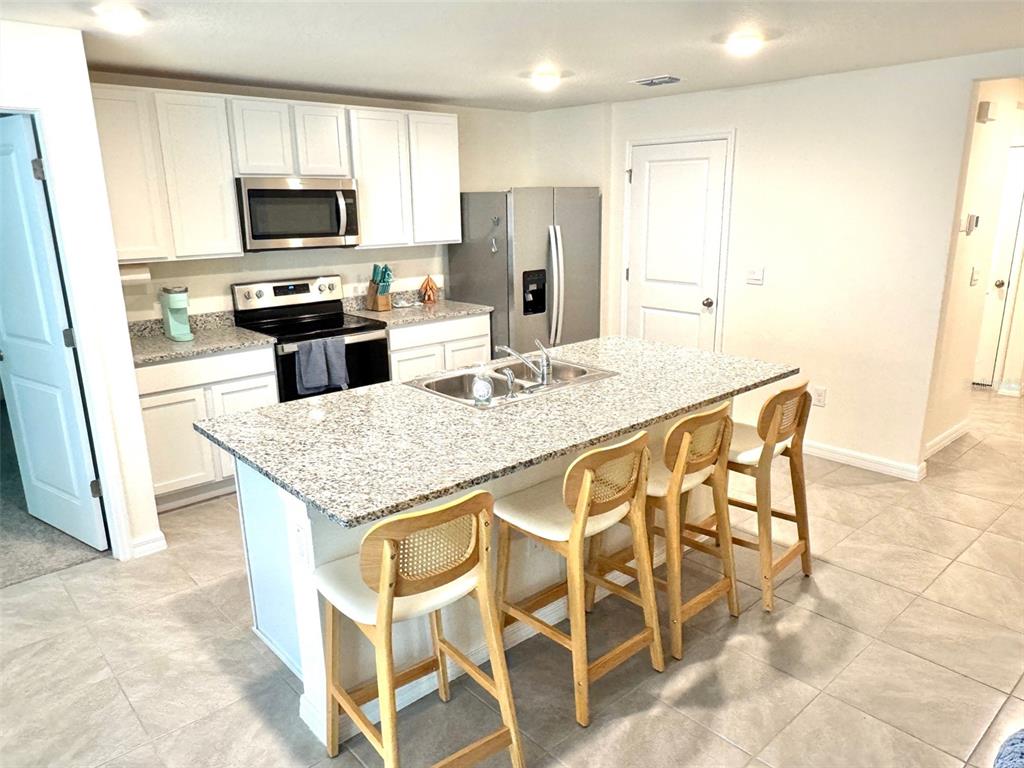 13374 Mylion Way Spring Hill, FL 34610 - Photo 7 of 39 a kitchen with stainless steel appliances kitchen island granite countertop a table chairs microwave and refrigerator
