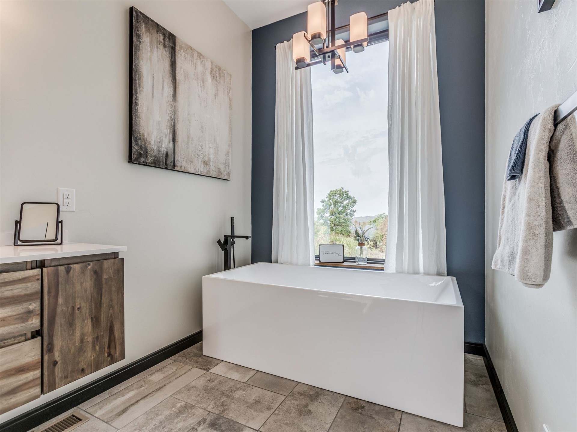 1073 Hidden Ridge Road Stigler, OK 74462 - Photo 35 of 56 Freestanding soaking tub with a floor-mounted bath filler, wood-finish vanity with a white countertop, and tile flooring