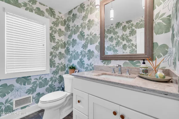 a bathroom with a granite countertop sink and a toilet