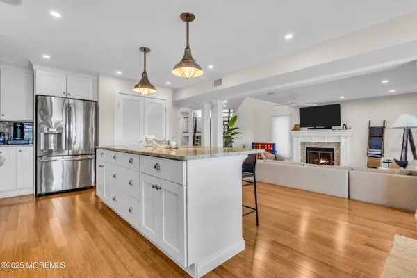 a kitchen with granite countertop a refrigerator a stove top oven a sink dishwasher and white cabinets with wooden floor