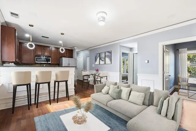 a living room with stainless steel appliances kitchen island granite countertop furniture and a wooden floor