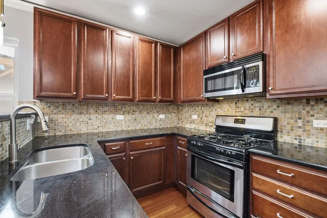 a kitchen with granite countertop wooden cabinets stainless steel appliances and a sink