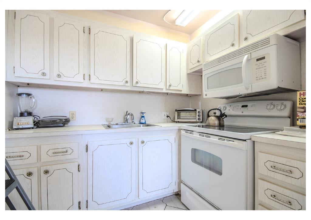 251 Preston F, Unit 251 Boca Raton, FL 33434 - Photo 12 of 35 a kitchen with granite countertop white cabinets and white appliances