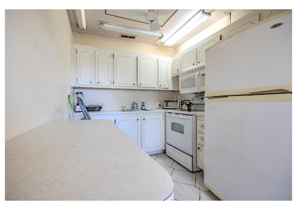 251 Preston F, Unit 251 Boca Raton, FL 33434 - Photo 17 of 35 a kitchen with white cabinets and white appliances