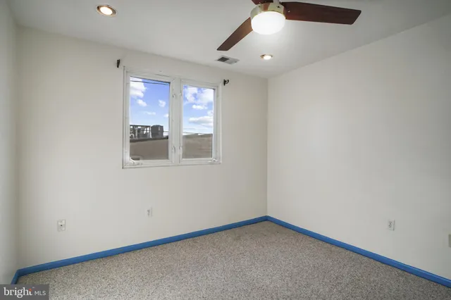 an empty room with a window and ceiling fan